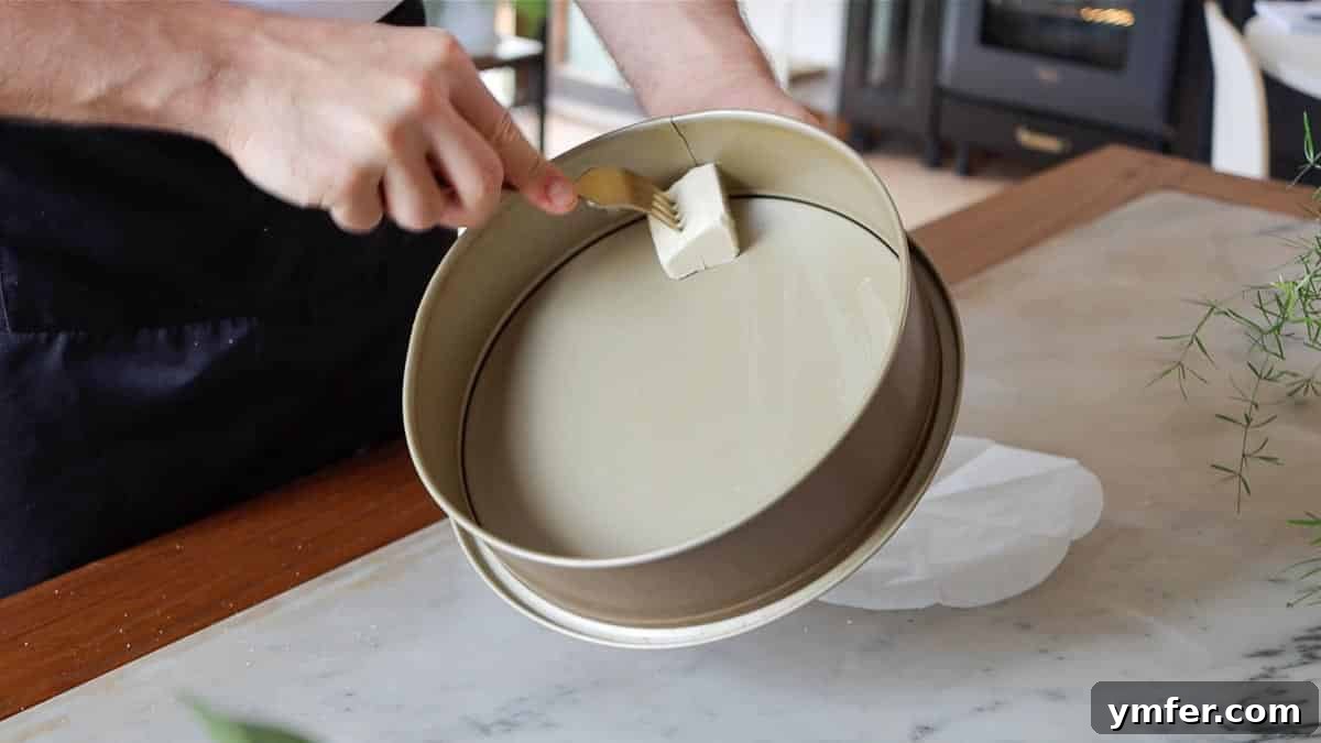 Decadent Chocolate Brownie Cake 5 Brushing a springform pan with butter to prepare for baking with parchment paper