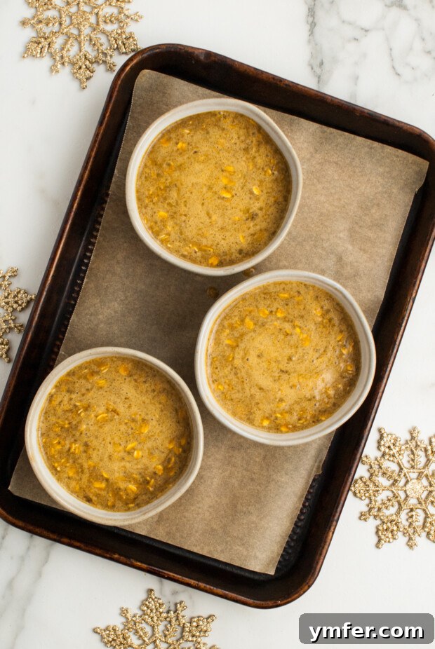 Cozy Gingerbread Oat Bake 8 Unbaked Gingerbread Oatmeal mixture in individual bowls on a sheet pan.