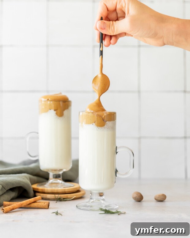 Velvet Eggnog Coffee Indulgence 2 Spooning whipped coffee over eggnog, creating a beautiful layered drink.