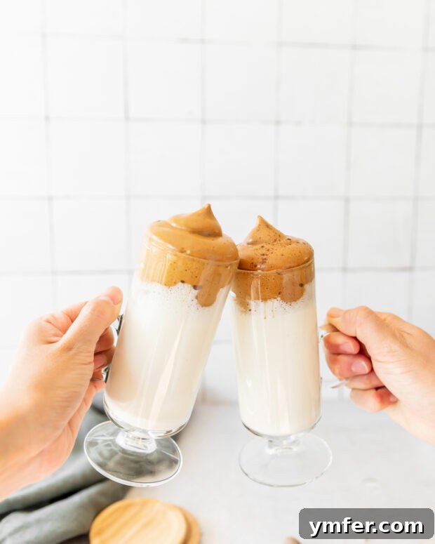 Velvet Eggnog Coffee Indulgence 5 Two people clinking festive glasses of Eggnog Whipped Coffee together in a celebratory toast.