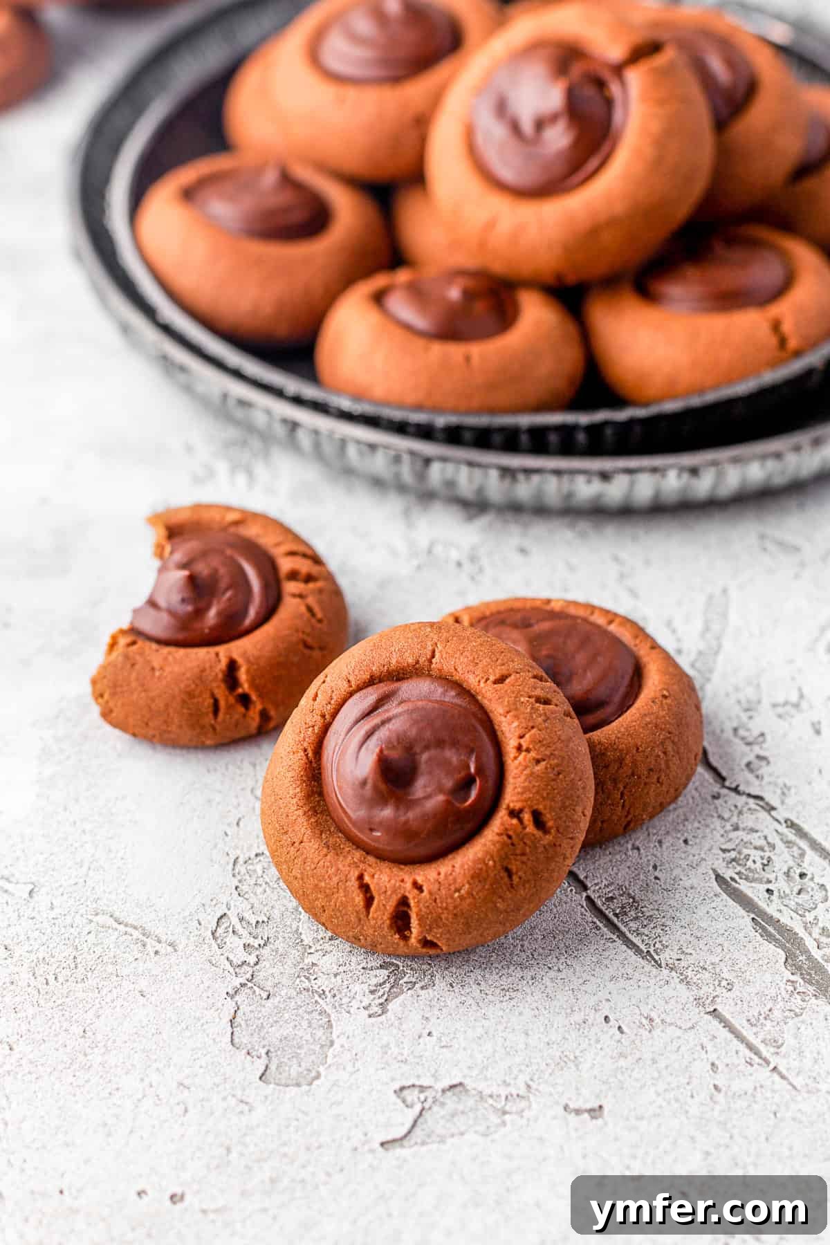 Rich Double Chocolate Thumbprint Gems 5 A plate of freshly baked Double Chocolate Thumbprint Cookies in the foreground, with more cookies artfully arranged in the background, hinting at an abundance of treats.