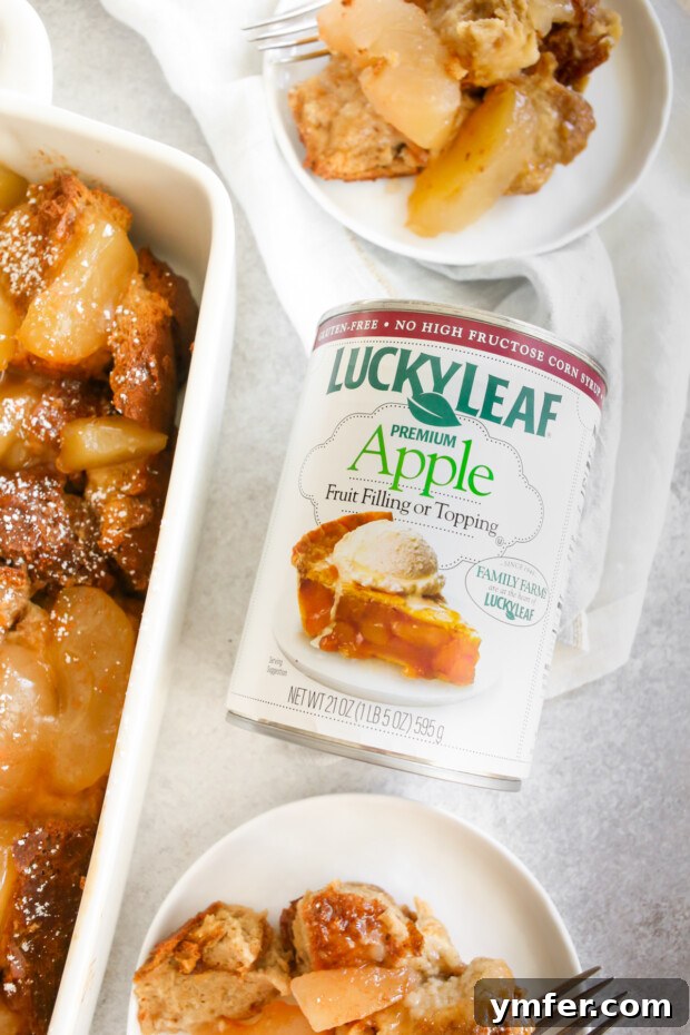 A can of Lucky Leaf apple pie filling sits prominently on a table, flanked by two plates of freshly baked Apple Pie Baked French Toast.