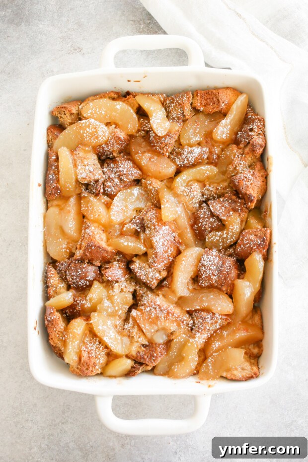 A warm, bubbling Apple Pie Baked French Toast casserole in a beautiful ceramic serving dish, ready for family and friends to enjoy.