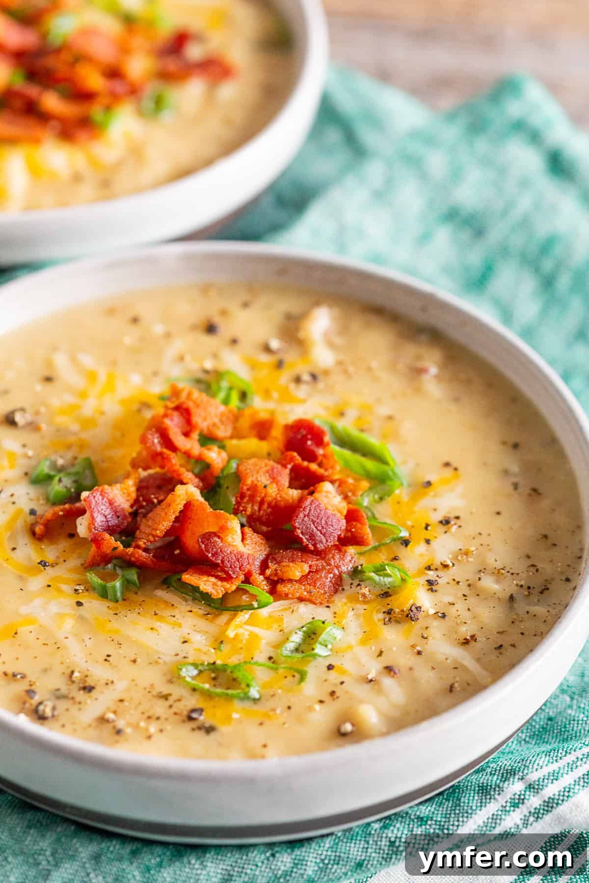 Hearty Loaded Potato Chowder 3 Close-up shot of creamy loaded baked potato soup, being topped with freshly cooked, crumbled bacon.