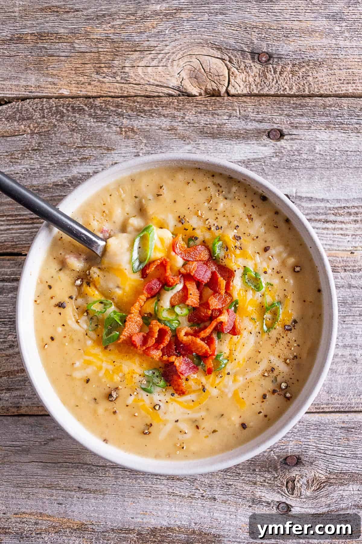 Hearty Loaded Potato Chowder 6 A generous bowl of loaded baked potato soup, garnished with a medley of crispy bacon, chopped green onions, and melted shredded cheese.