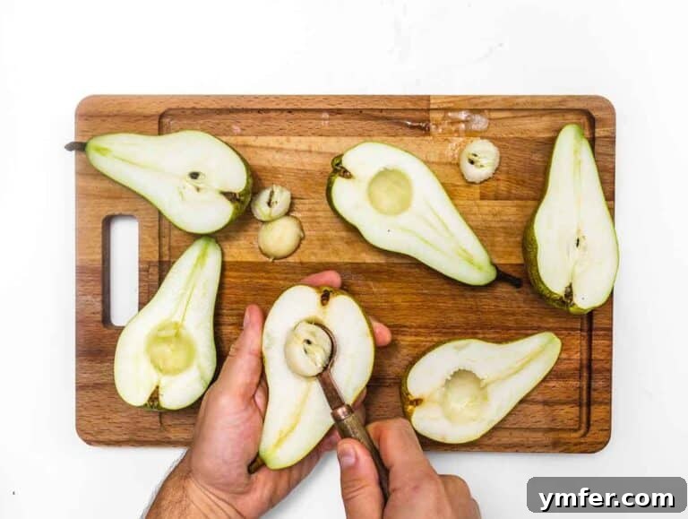 Scooping out the core of a pear half with a spoon.
