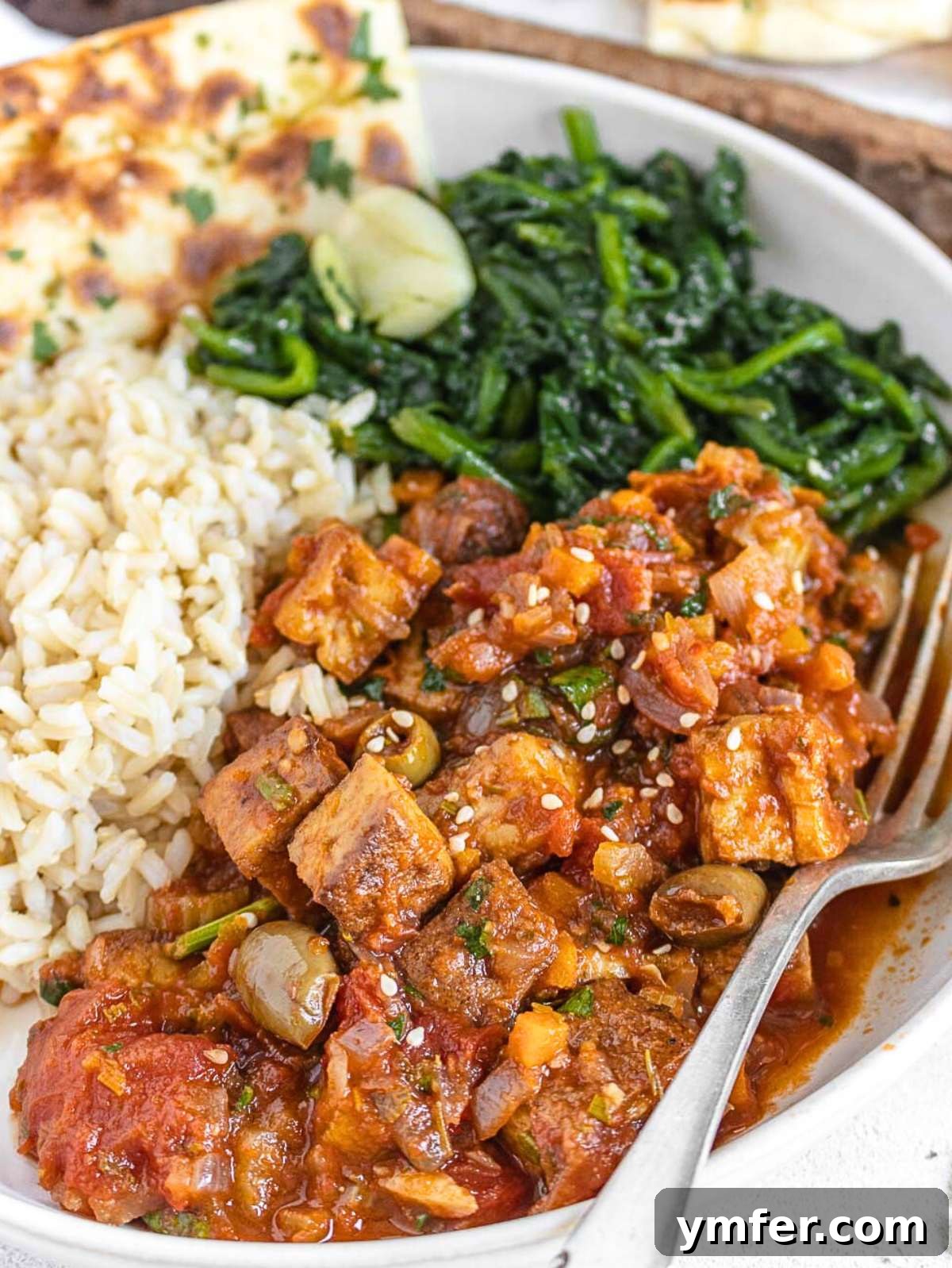 The Forager's Tofu Cacciatore 2 A fork piercing a piece of tofu cacciatore, served alongside fluffy white rice, showcasing the tender texture and rich sauce.