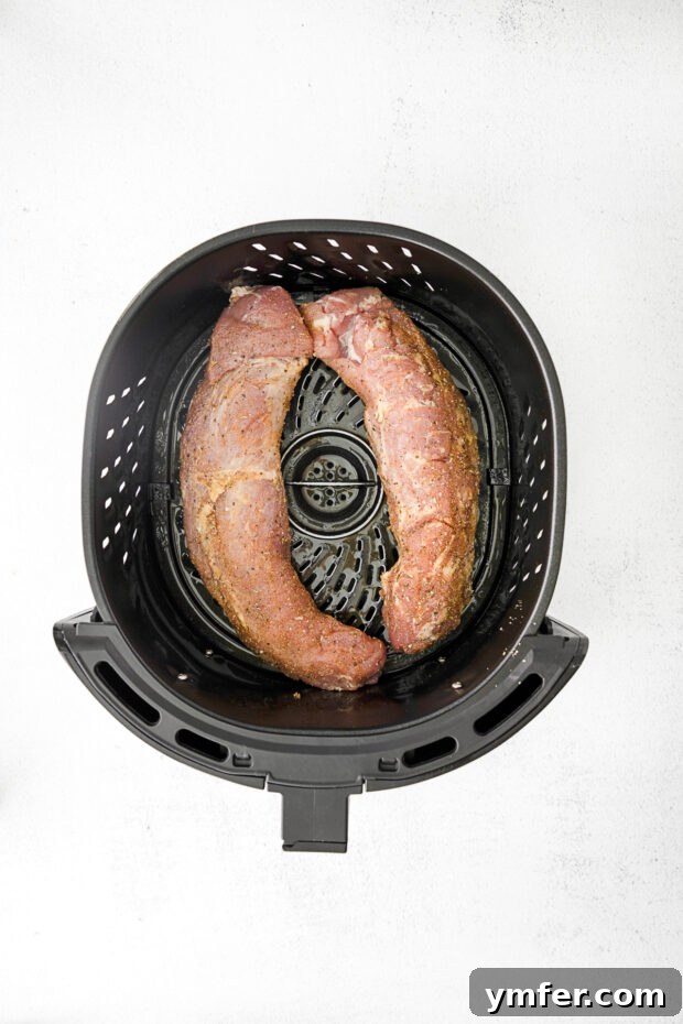 Perfect Air Fryer Pork Tenderloin 4 Uncooked pork tenderloin seasoned and ready for the air fryer basket.