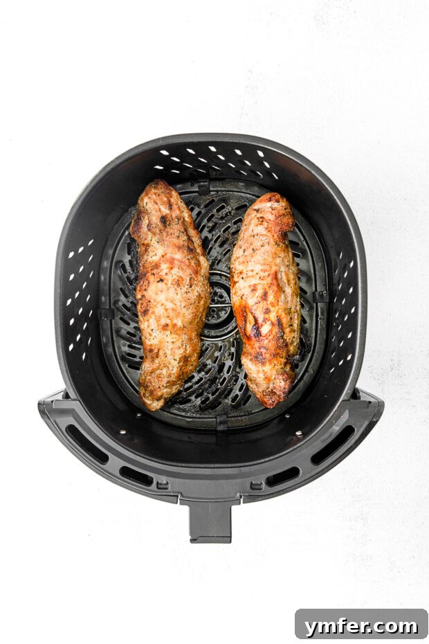 Perfect Air Fryer Pork Tenderloin 5 Perfectly cooked pork tenderloin resting in an air fryer basket after cooking.