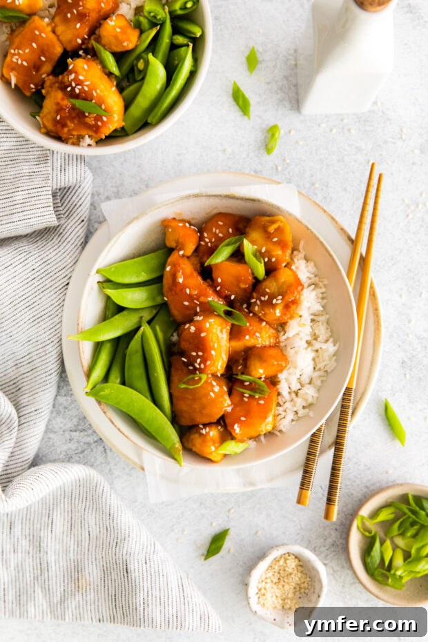 Sticky Honey Garlic Chicken Bowls 2 Honey Garlic Chicken Bowls served in a bowl with chopsticks and green onion.