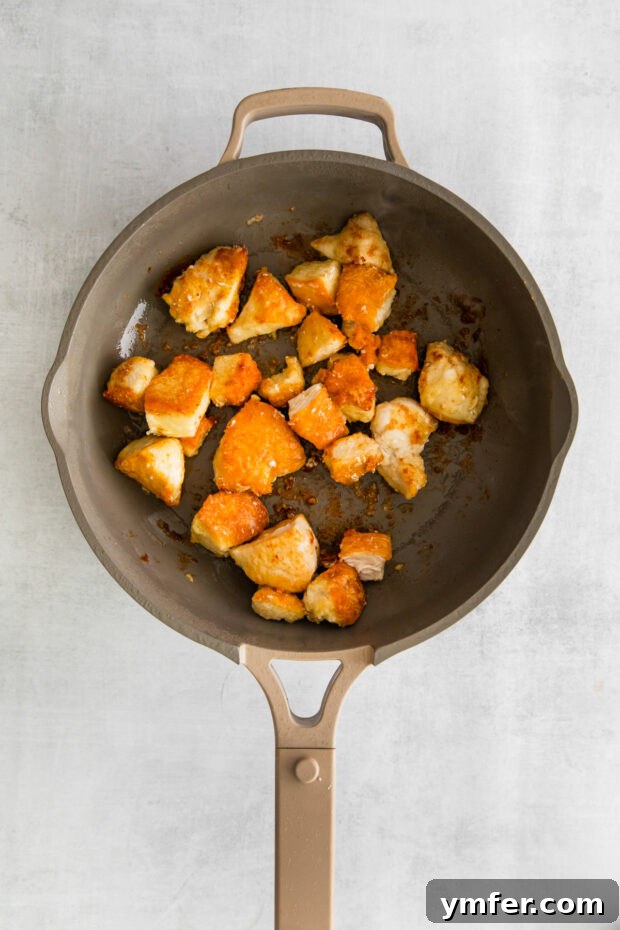 Sticky Honey Garlic Chicken Bowls 5 Crispy golden-brown chicken searing in a pan.