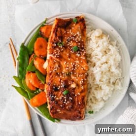 Cooked Air Fryer Miso Salmon on a plate with rice, garnished with fresh herbs.