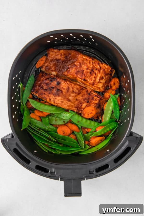 Air Fried Miso-Glazed Salmon 5 Cooked Air Fryer Miso Salmon in the air fryer basket, perfectly glazed and flaky, surrounded by tender-crisp vegetables.