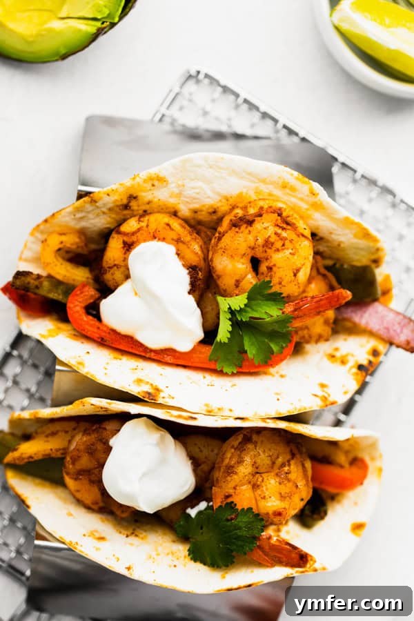 One-Pan Shrimp Fajitas 2 Freshly cooked Sheet Pan Shrimp Fajitas served with a dollop of sour cream and a sprinkle of cilantro, ready to be wrapped in a tortilla.