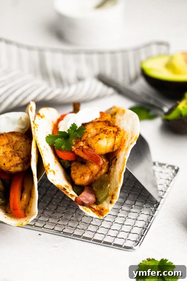 One-Pan Shrimp Fajitas 5 Close-up of Sheet Pan Shrimp Fajitas, featuring seasoned shrimp, peppers, and onions, neatly tucked into a warm tortilla.