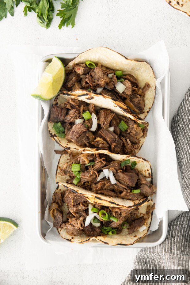 Melt-in-Your-Mouth Slow Cooker Beef Barbacoa 2 Tender Slow Cooker Beef Barbacoa, shredded and garnished with fresh green onions, ready to serve.