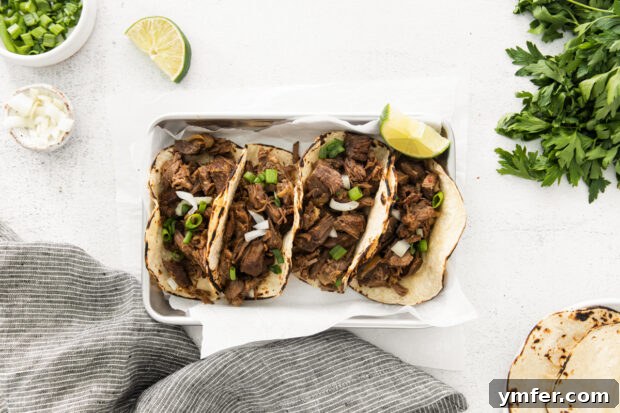 Melt-in-Your-Mouth Slow Cooker Beef Barbacoa 7 A close-up shot of shredded Slow Cooker Beef Barbacoa served on a plate, garnished with fresh cilantro and a lime wedge, highlighting its juicy texture.
