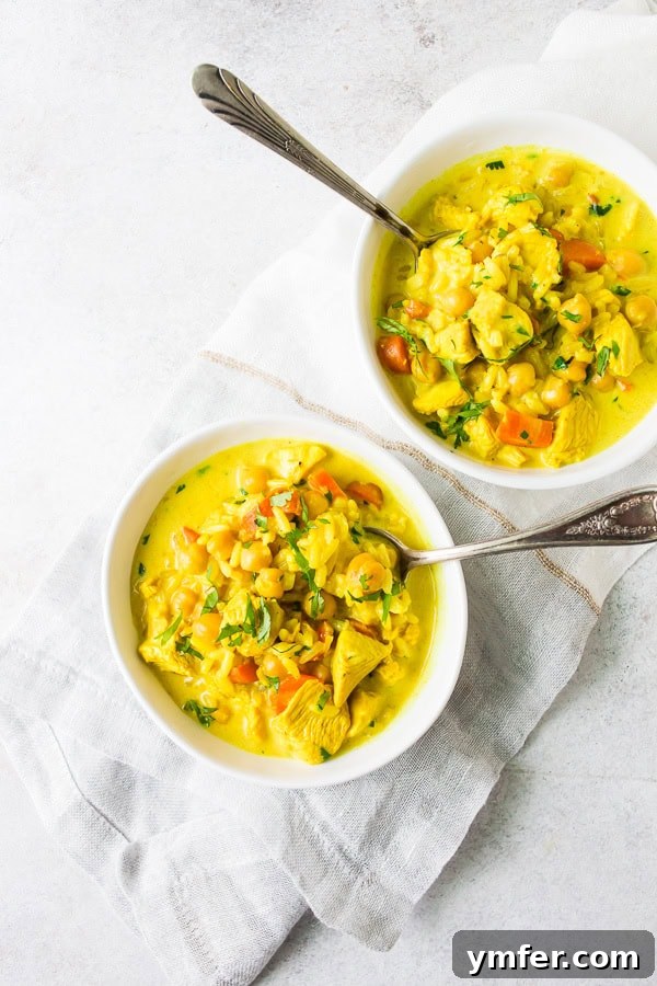Creamy Golden Turmeric Chicken Soup 2 Chicken Coconut Milk Turmeric Soup served in two small white bowls with spoons, garnished with fresh herbs.