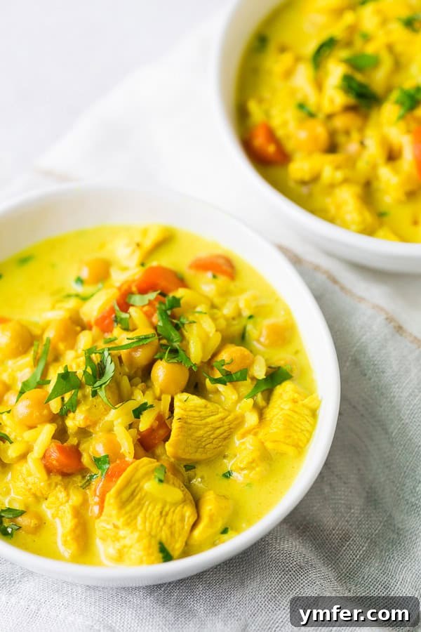 Creamy Golden Turmeric Chicken Soup 3 A close-up shot of Chicken Coconut Milk Turmeric Soup topped with minced fresh herbs, highlighting its rich color and texture.