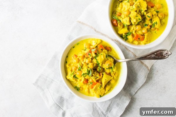 Creamy Golden Turmeric Chicken Soup 5 A bowl of Chicken Coconut Milk Turmeric Soup with a spoon, highlighting the rich broth and ingredients.