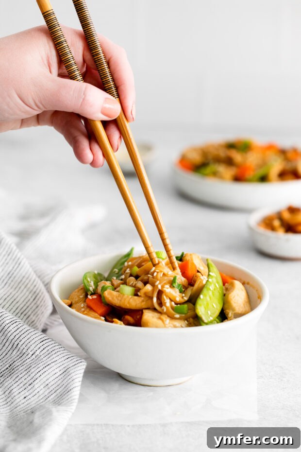 Savory Cashew Chicken Pad Thai 5 Cashew Chicken Pad Thai with a hand holding chopsticks picking up the noodles.