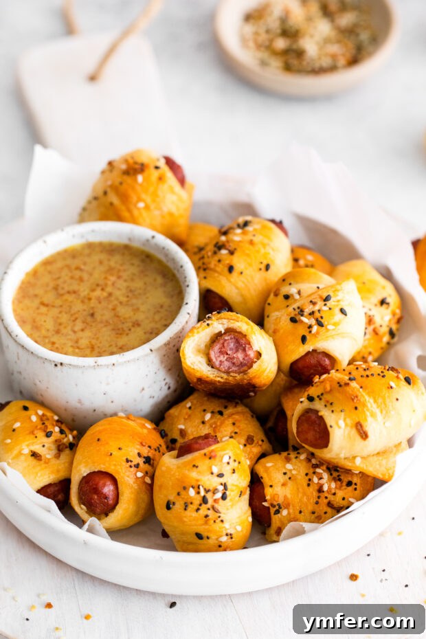 Crunchy Everything Piggy Rolls 10 Everything Bagel Pigs in a Blanket served in a dish with sauce.