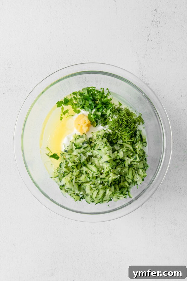 Refreshing Cucumber Yogurt Dip 5 All Tzatziki sauce ingredients, including Greek yogurt, shredded cucumber, and herbs, gathered in a bowl before mixing.
