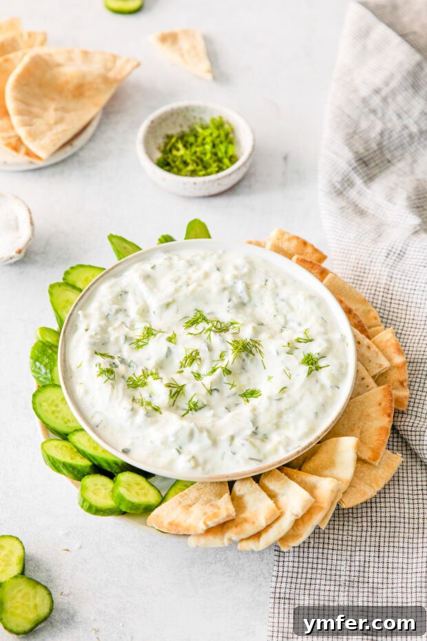 Refreshing Cucumber Yogurt Dip 8 A close-up of Tzatziki sauce in a bowl, garnished with a sprig of fresh dill, emphasizing its fresh ingredients.