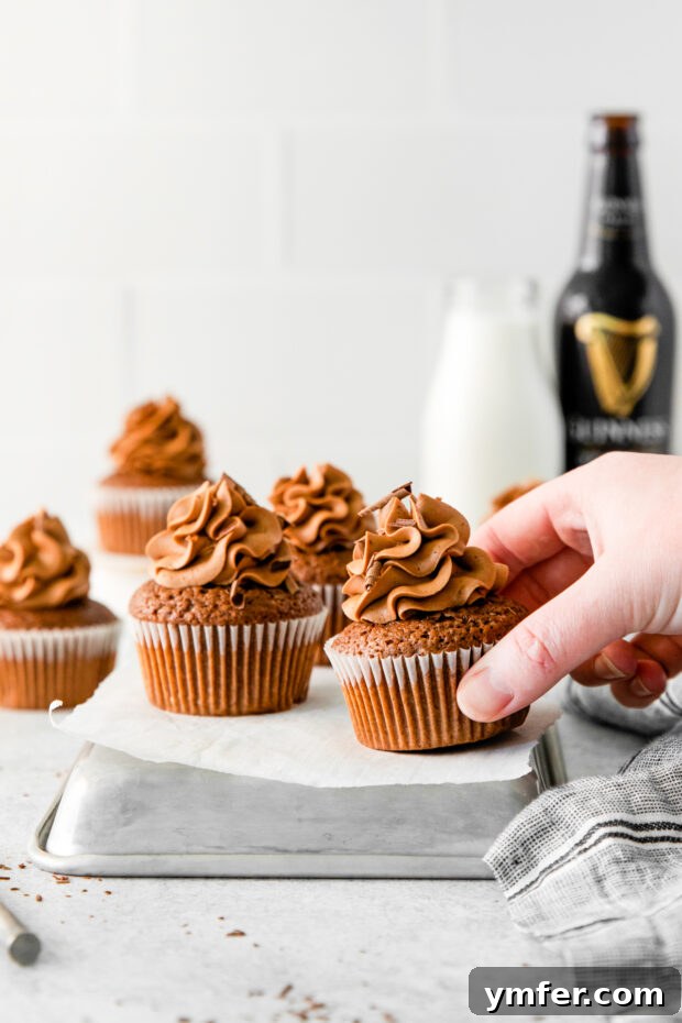 Velvet Stout Chocolate Cupcakes 11 A hand reaching for a perfectly frosted Chocolate Guinness Cupcake, highlighting its irresistible appeal.