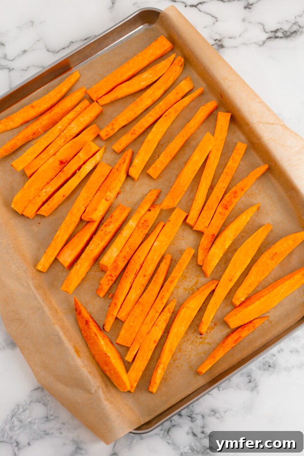 Gourmet Sweet Potato Fries 4 Uncooked sweet potato sticks, perfectly cut and arranged in a single layer on a sheet pan, ready for baking.