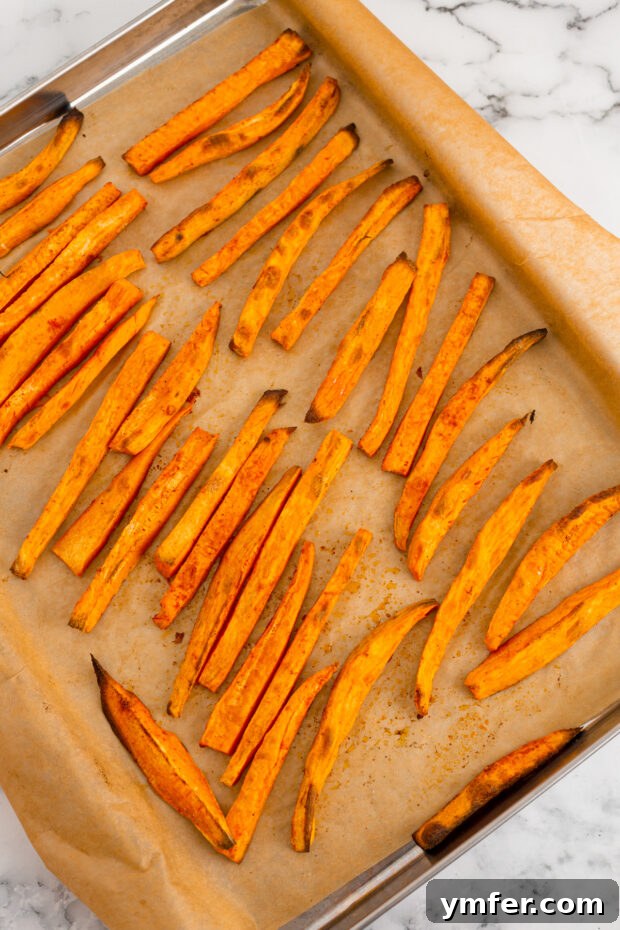 Gourmet Sweet Potato Fries 5 Golden-brown, crispy sweet potato fries on a sheet pan, cooked to perfection and lightly glistening with oil.