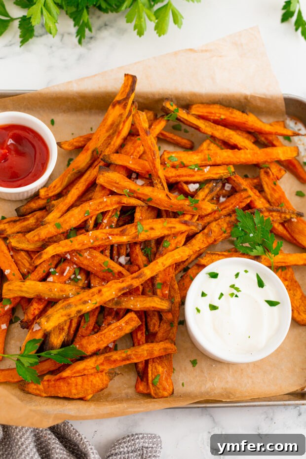 Gourmet Sweet Potato Fries 6 A vibrant plate of sweet potato fries served with three different dipping sauces: ketchup, a creamy white sauce, and a yellowish honey mustard.