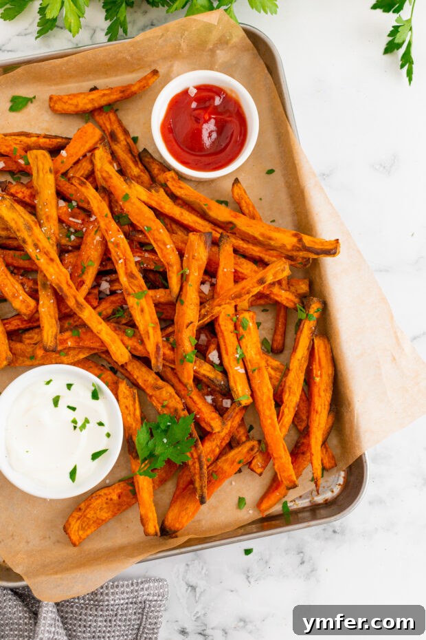 Gourmet Sweet Potato Fries 8 A small, oval sheet pan filled with golden, baked sweet potato fries, neatly arranged and ready to be served.