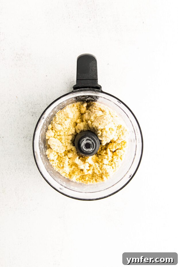 Cloud-Kissed Lemon Tartlets 4 Raw pastry dough being mixed in a food processor, showcasing the process of achieving the perfect crumbly texture.