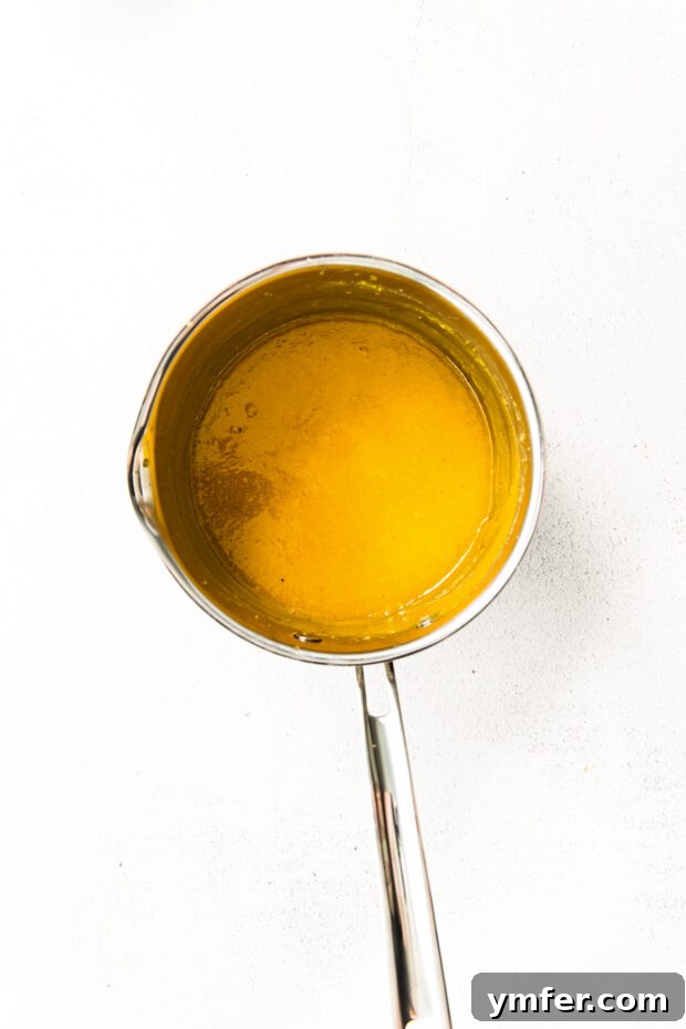 Cloud-Kissed Lemon Tartlets 6 Smooth, glossy lemon curd simmering gently in a saucepan, showing its rich texture and vibrant color as it thickens.
