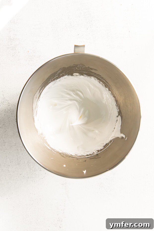 Cloud-Kissed Lemon Tartlets 8 Light and airy whipped meringue, forming stiff peaks in a mixing bowl, ready to be piped onto the tarts.
