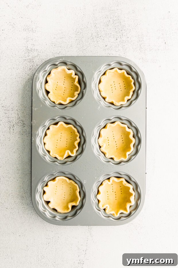 Cloud-Kissed Lemon Tartlets 9 Delicate pastry dough pressed into a mini tart pan, ready for blind baking, showcasing the perfect fit.