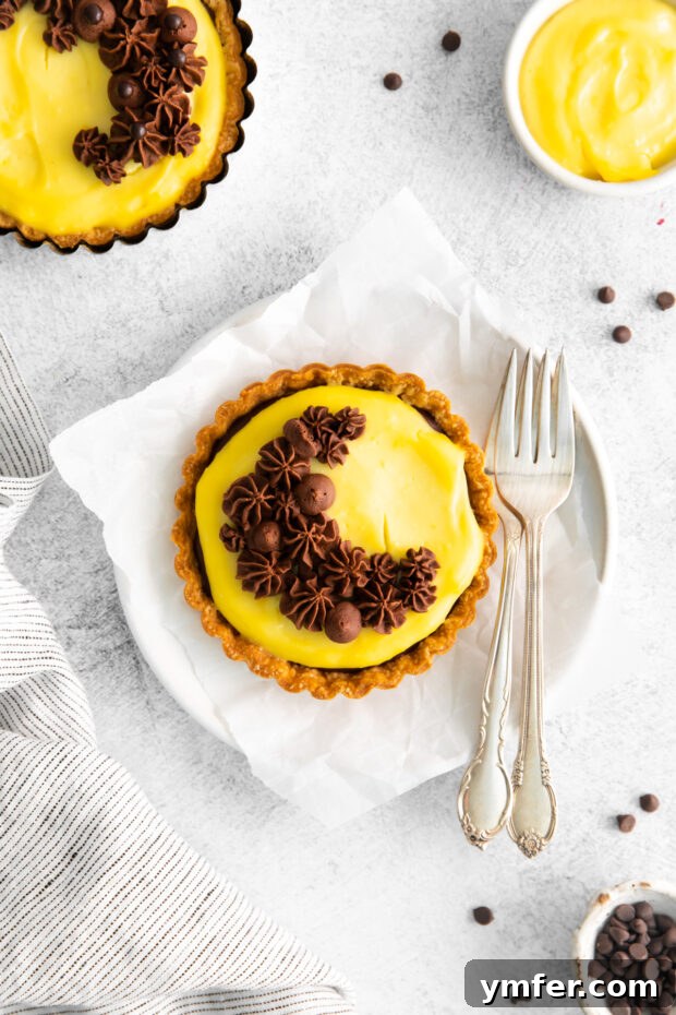 Mini Boston Cream Delights 2 Boston Cream Pie Tarts served with two forks, highlighting the layers of crust, cream, and ganache.