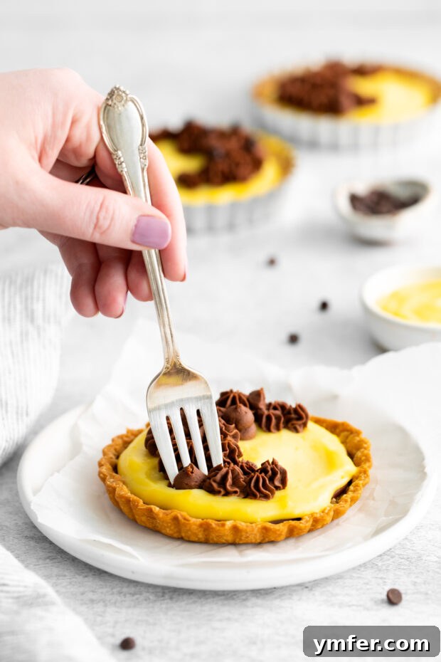 Mini Boston Cream Delights 5 A fork taking a bite out of a Boston Cream Pie Tart, showing the layers clearly.