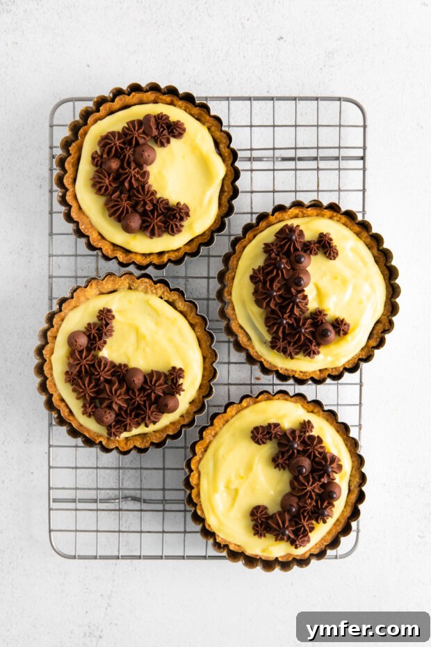 Mini Boston Cream Delights 8 Assembled Boston Cream Pie Tarts cooling on a wire rack.