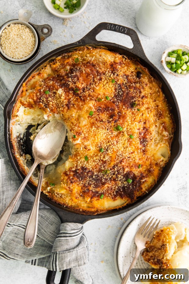 Ultimate Homemade Scalloped Potatoes 11 Homemade Scalloped Potatoes in a skillet with a serving spoon and a decorative serving utensil.