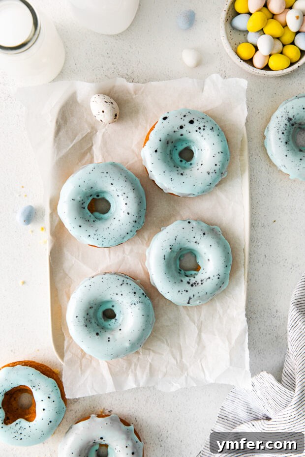 Robin's Egg Blue Baked Donuts 2 Robin's Egg Baked Donuts sitting on parchment paper, showcasing their beautiful blue glaze and speckles.