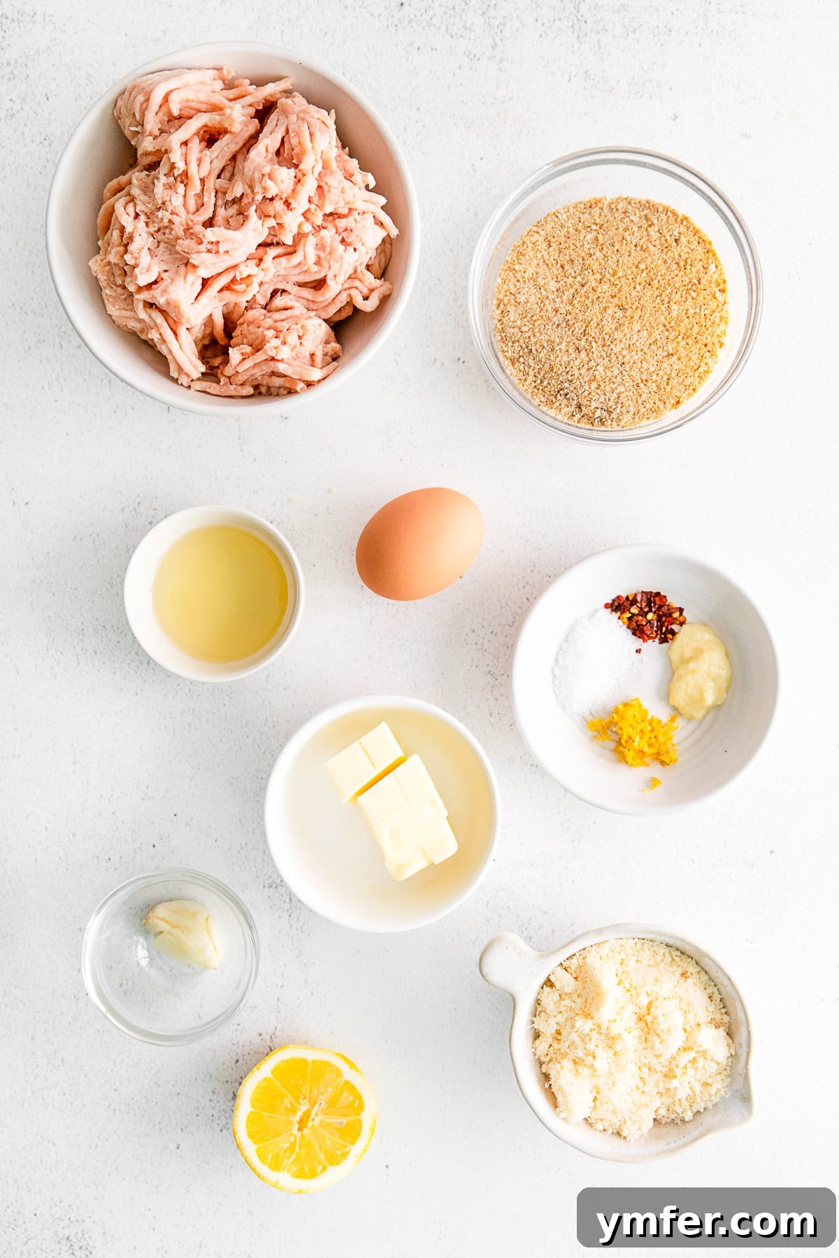 Crispy Air Fryer Chicken Meatballs 3 Fresh ingredients laid out on a wooden table, including ground chicken, lemons, garlic, breadcrumbs, and a bowl of spices, ready to make air fryer chicken meatballs.
