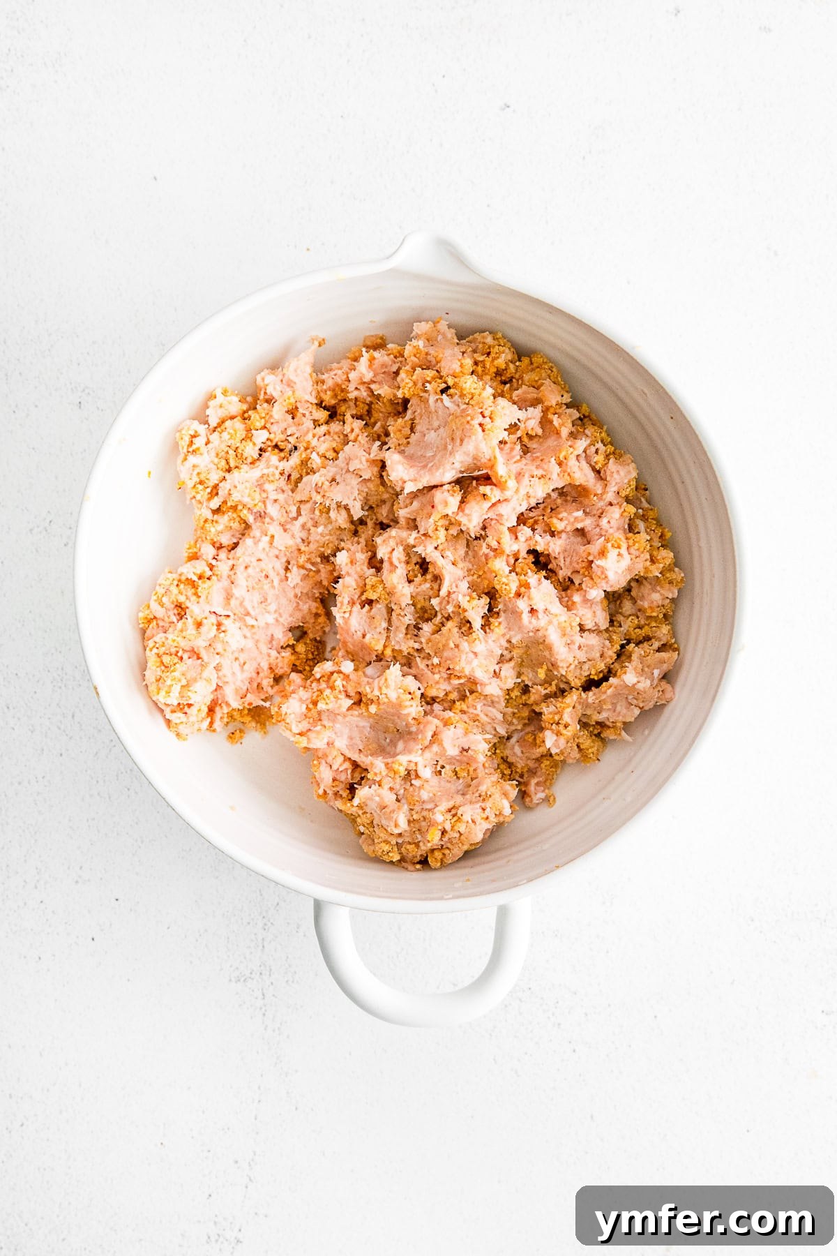 Crispy Air Fryer Chicken Meatballs 4 A close-up of the meatball mixture in a glass bowl, showcasing the combined texture of ground chicken, breadcrumbs, and spices before being rolled into balls.