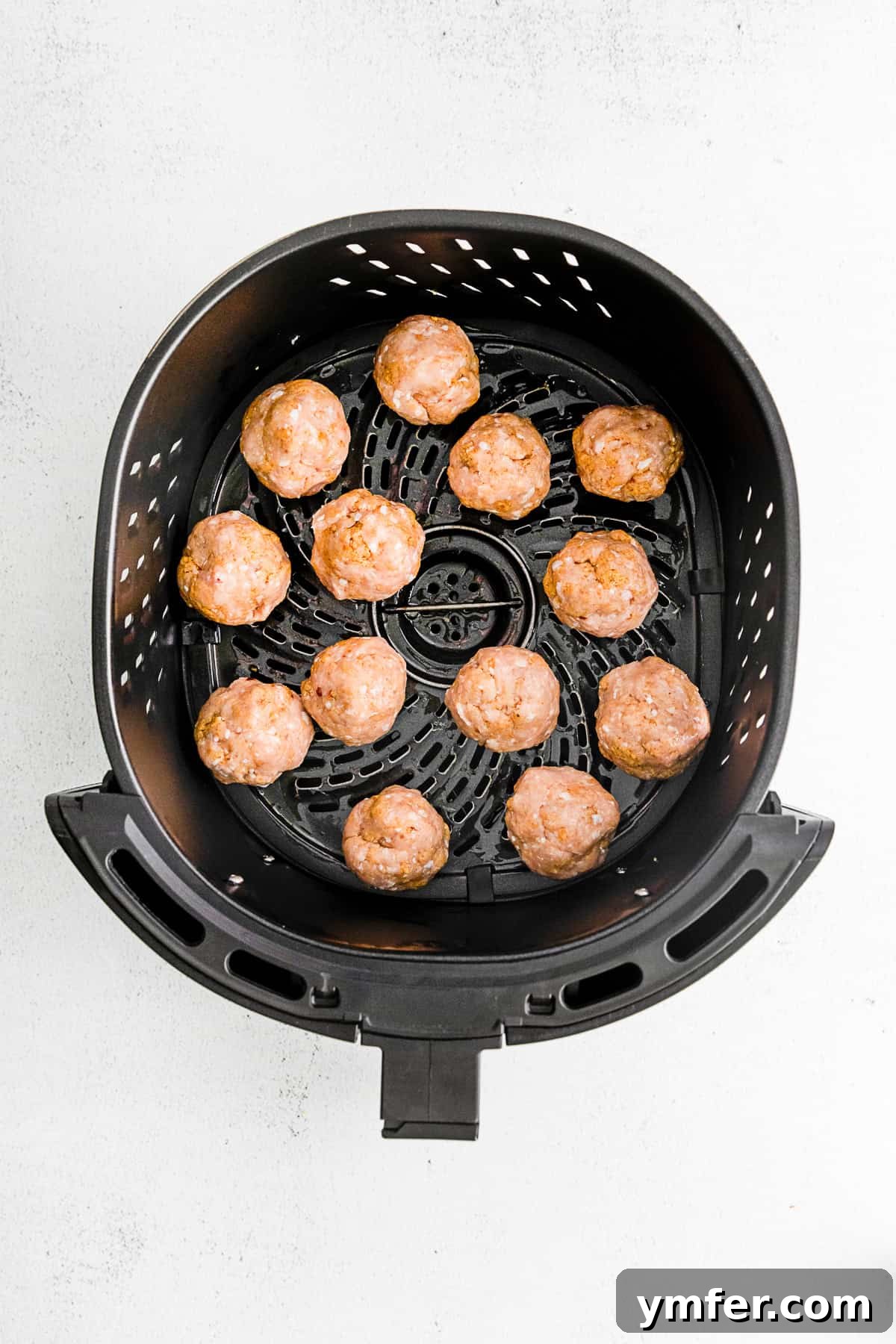 Crispy Air Fryer Chicken Meatballs 5 Uncooked air fryer chicken meatballs neatly arranged in a silver air fryer basket, ready for cooking.