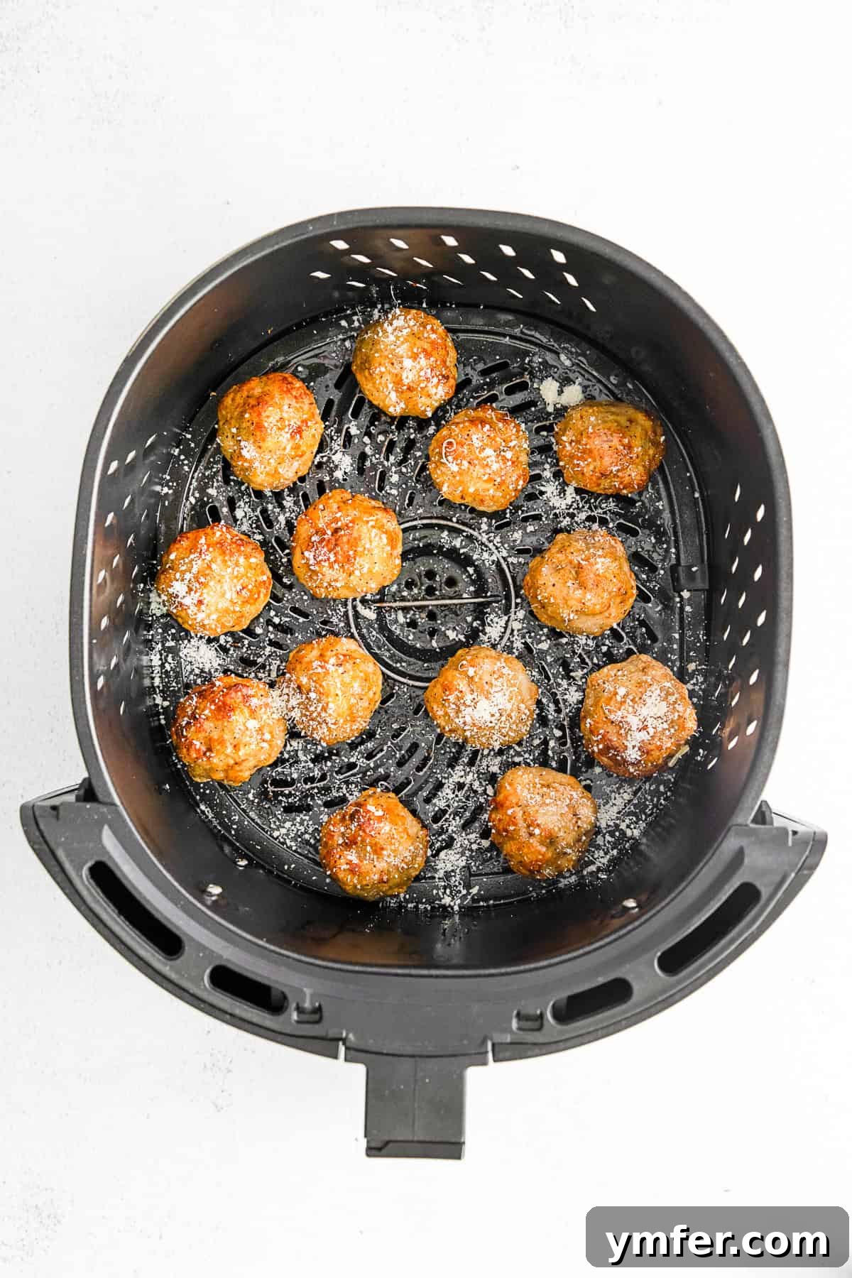 Crispy Air Fryer Chicken Meatballs 6 Perfectly cooked and golden-brown chicken meatballs resting in an air fryer basket after being cooked.