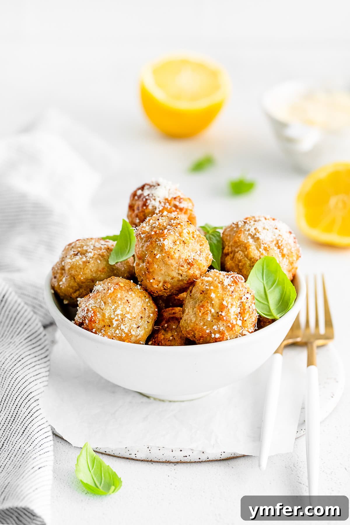 Crispy Air Fryer Chicken Meatballs 7 A bowl of air fryer chicken meatballs generously sprinkled with grated parmesan cheese and fresh parsley.