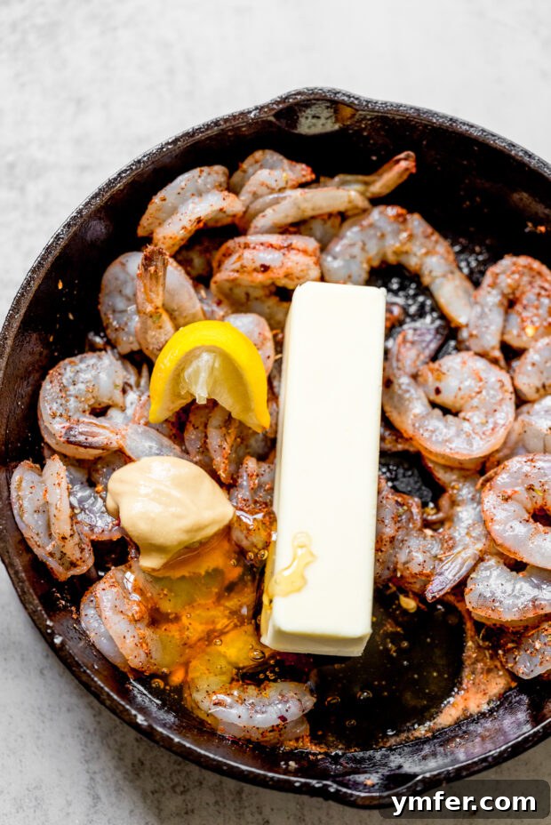 Cajun Honey Butter Shrimp with Creamy Grits 4 Raw shrimp seasoned with Cajun spices in a pan with melting butter.