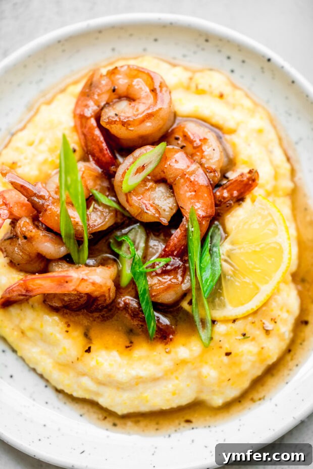 Cajun Honey Butter Shrimp with Creamy Grits 5 A serving of Cajun Honey Butter Shrimp and Grits, garnished with lemon wedges and chopped green onions.