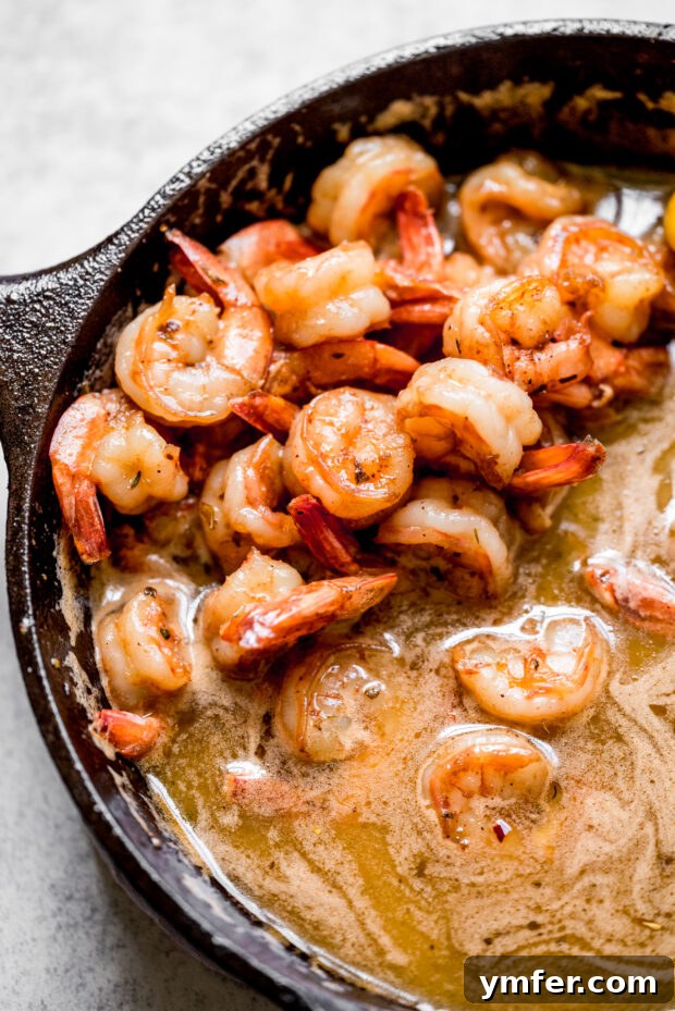 Cajun Honey Butter Shrimp with Creamy Grits 6 Cajun Honey Butter Shrimp cooking in a skillet, coated in a rich, sweet, and spicy sauce.